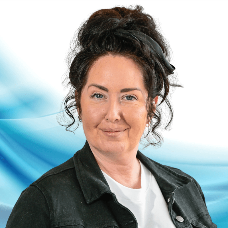 Smiling woman with dark hair in a black jacket and white shirt, posed against a blue abstract background.