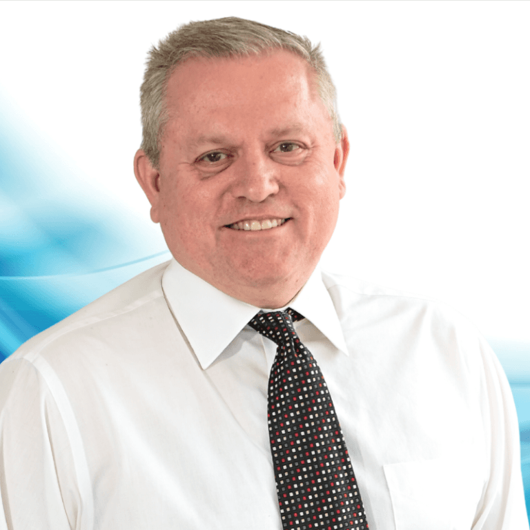 Professional headshot: smiling middle-aged man in a white shirt and patterned tie with a blue abstract background.